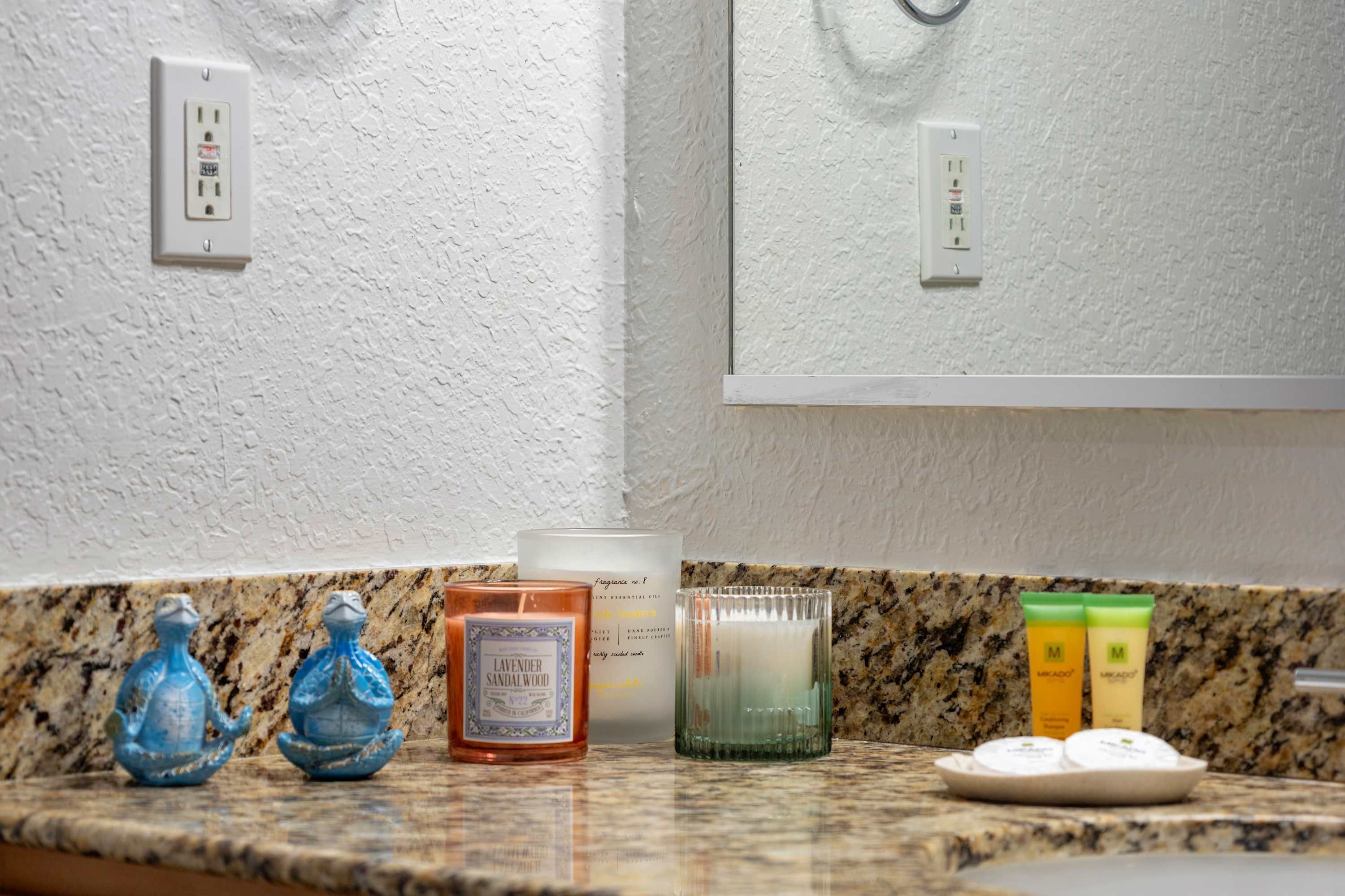 A bathroom counter with a granite countertop, a white textured wall, and a mirror reflecting the wall.