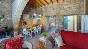 A rustic stone interior with a dining area, a sofa, and a fireplace. - AKAMANTIDA PLATEA 1. A 3-bedroom country house built in 1900, renovated in 2016. (Pano Arodes)