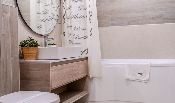 A bathroom with a white sink, wooden vanity, a round mirror, and a shower curtain with text. - MoHost Urban Plaza (Brasov)