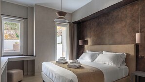 A modern hotel room with a large bed, a desk, and a view of the outdoors. - Pool & SPA Vatican Luxury Apt (Roma)