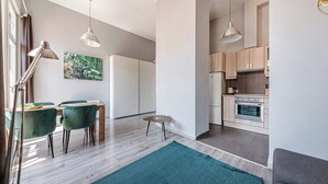 Una cocina moderna con armarios de madera, horno empotrado y zona de comedor con mesa y sillas.