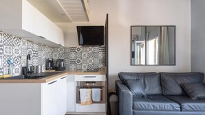 Un espacio habitable compacto con kitchenette, un sofá y una televisión.