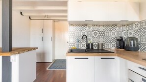 Una cocina con un salpicadero decorado, un fregadero, una cafetera y un hervidor.
