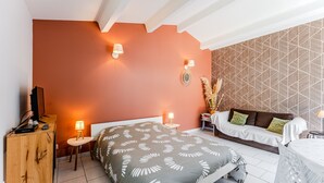 Een slaapkamer met een bed, nachtkastjes, een televisie en een behang met patroon.