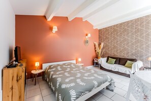 Een slaapkamer met een bed, nachtkastjes, een televisie en een behang met patroon.