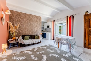 Een moderne woonkamer met een behang, een bank, een bijzettafeltje en een keuken op de achtergrond.