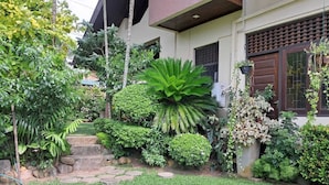 Una casa con un jardín cuidado, con diversas plantas y un sendero de piedra que lleva a la entrada.