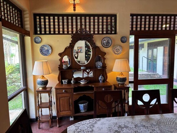 A traditional room with a wooden desk, two lamps, a mirror, and a view of the outdoors through a large window. - 19 St. Stephen's Villa (Colombo)