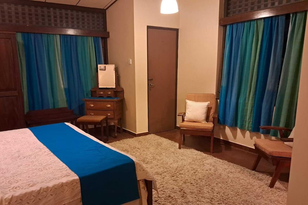 Une chambre à coucher avec un lit, une chaise, une commode et une porte.