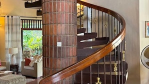 Una escalera de caracol con un columnilla de ladrillo, una barandilla de madera y una barandilla metálica con detalles decorativos.