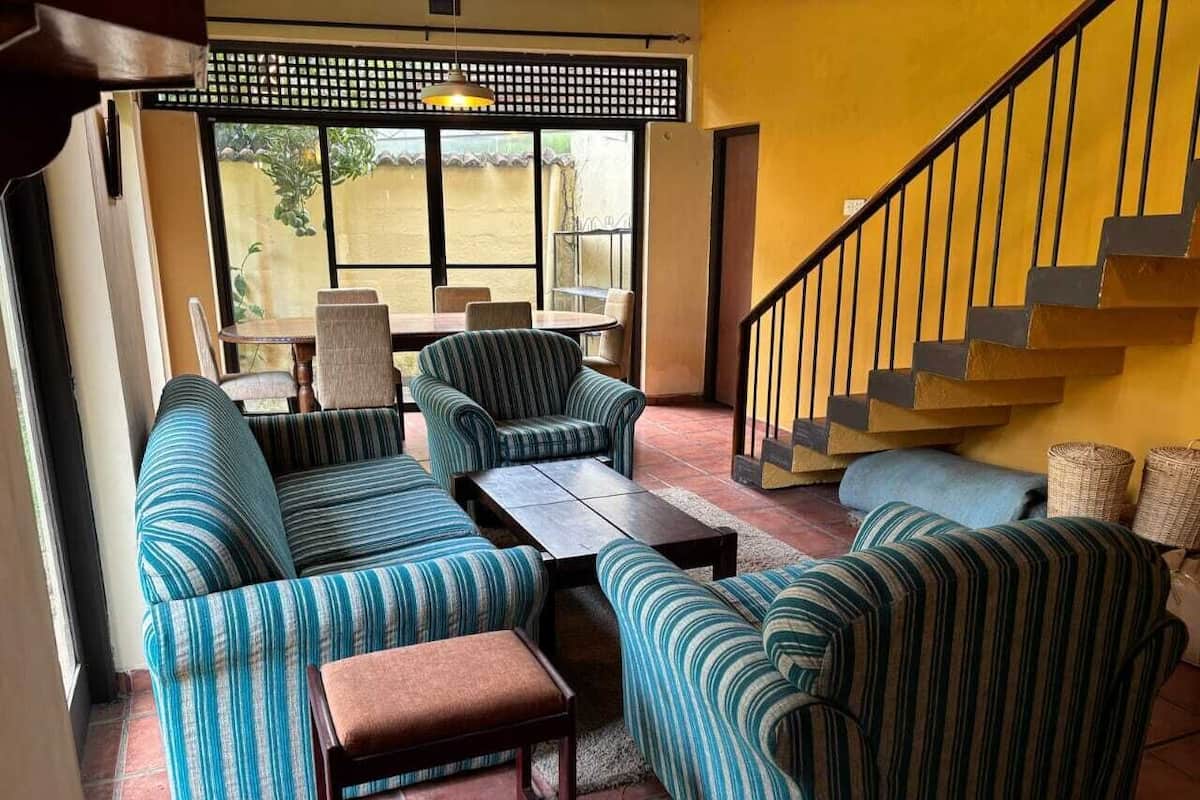 Un salon chaleureux avec des canapés à rayures, une table basse et un escalier.