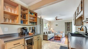 A kitchen with built-in cabinets, a coffee maker, and a dining area with a sofa and rug. - Private Hot Tub - Riverfront Cabin In Estes Park! (Estes Park)