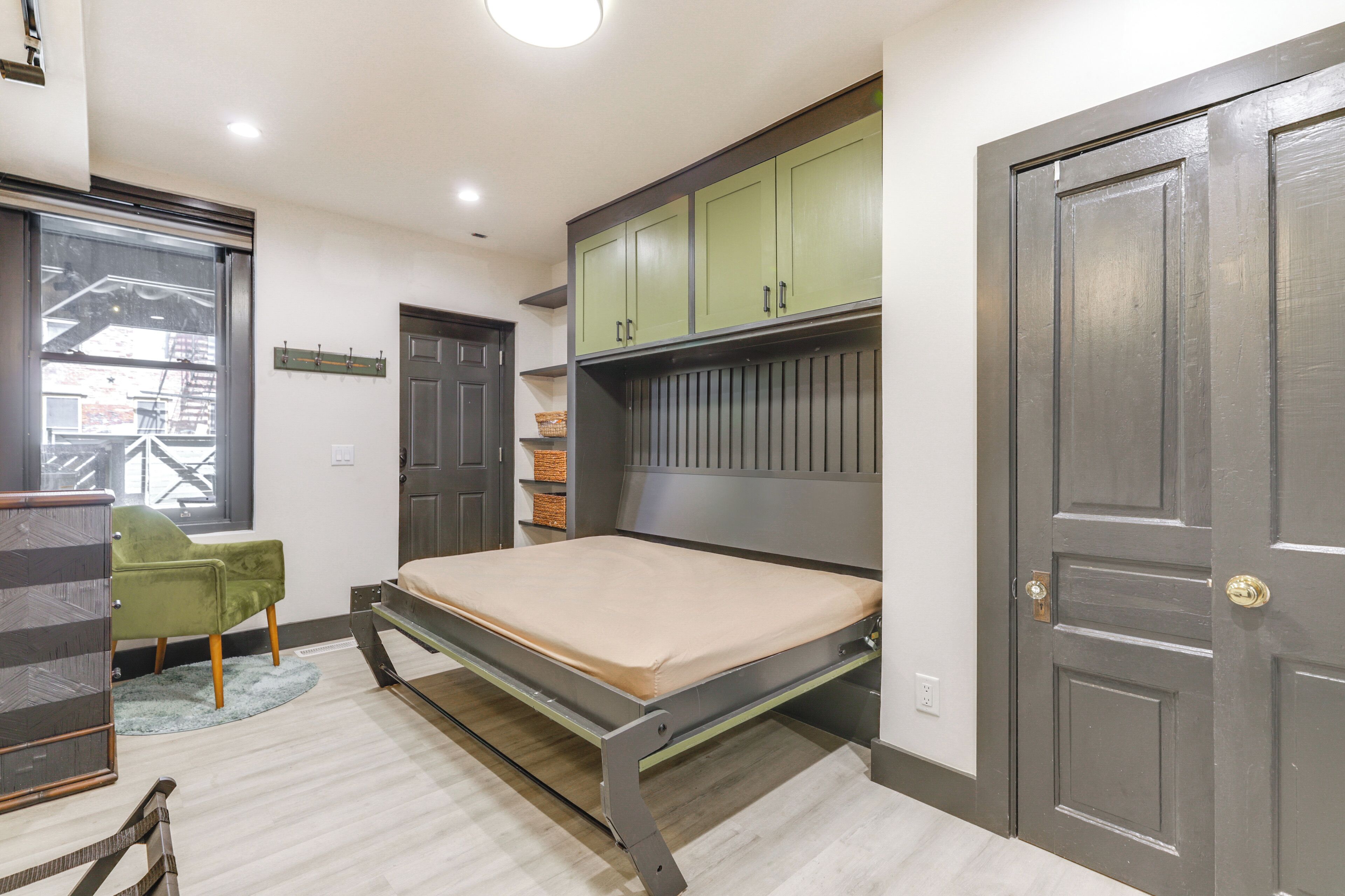 Un dormitorio con cama, una silla verde y un armario.