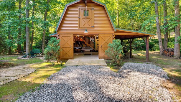 Un bâtiment en bois, de style grange, doté d’un porche abrité et entouré d’une zone boisée.