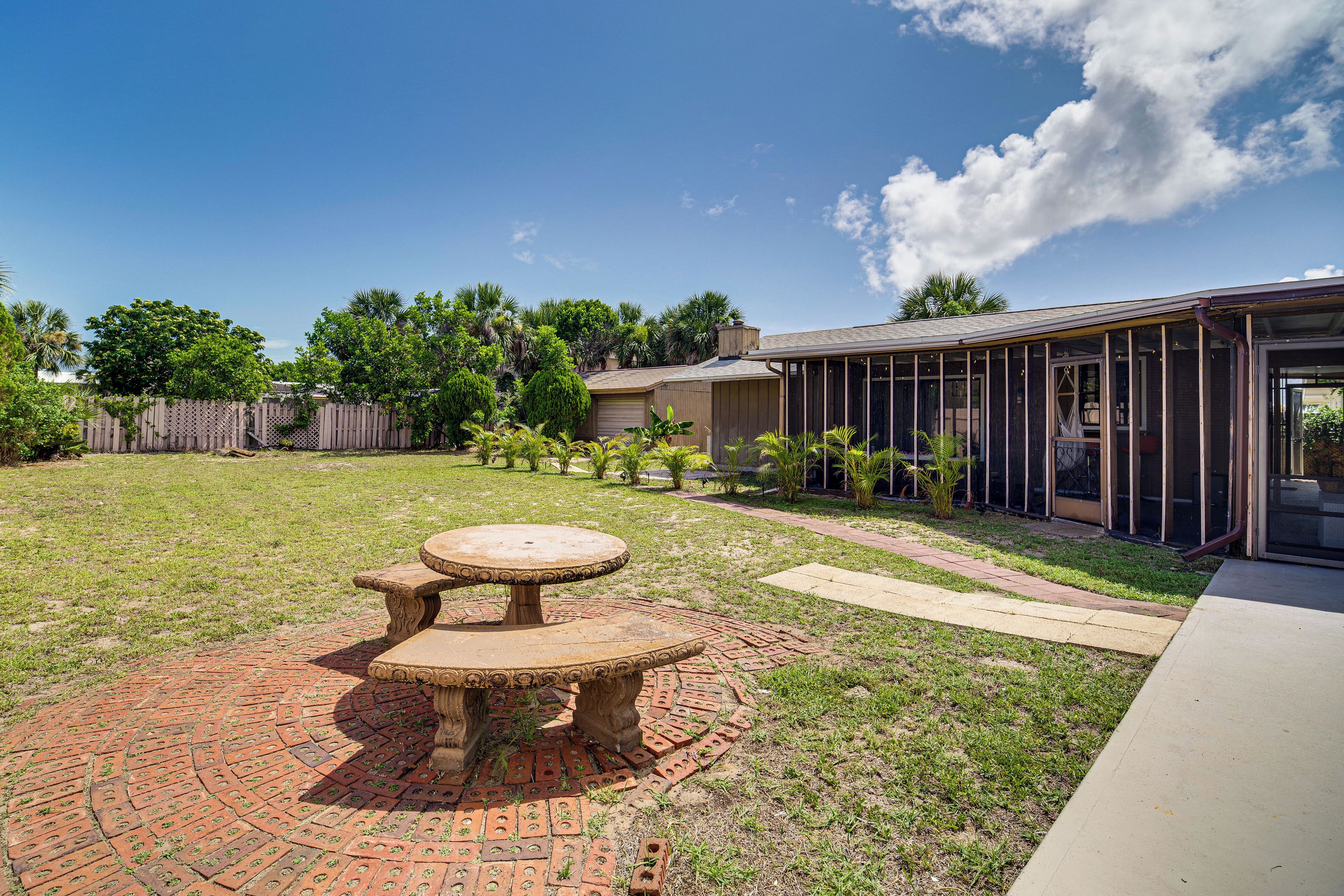 A backyard with a brick patio, a round table, and a house with a glass door.