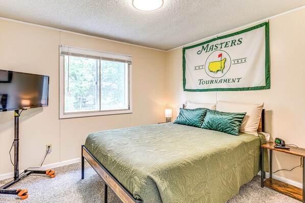 A bedroom with a bed, a television, a window, and a banner on the wall.