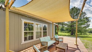 A covered deck with outdoor furniture, a large window, and a view of the surrounding landscape. - 5 Mi to Lake Ouachita: Peaceful Cabin Retreat (Royal)