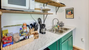 A kitchen with a microwave, coffee maker, and various kitchen utensils. There are shelves above the counter holding dishes and a framed picture on the wall. - 5 Mi to Lake Ouachita: Peaceful Cabin Retreat (Royal)