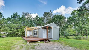 A small, single-story house with a porch and a deck, surrounded by a grassy yard and trees. - 5 Mi to Lake Ouachita: Peaceful Cabin Retreat (Royal)