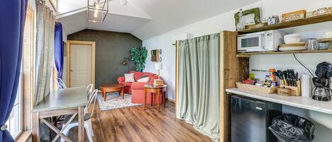 Een compact woongedeelte met een kitchenette, een eethoek en een zithoek met een bank en stoelen.