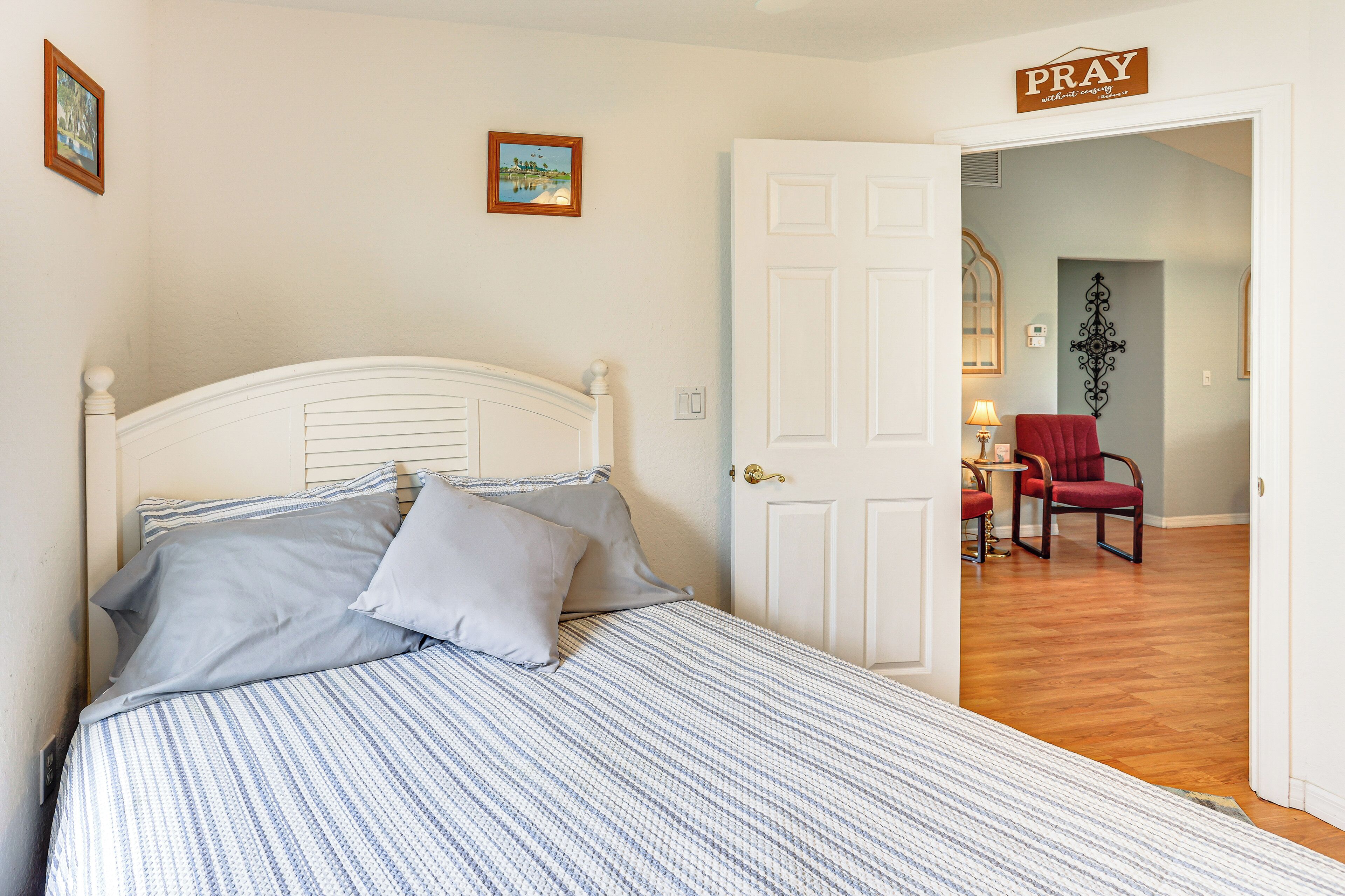 A bedroom with a bed, a door leading to another room, and a sign that says "PRAY".
