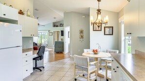 Une cuisine moderne avec des meubles blancs, une table à manger avec des chaises et un lustre.
