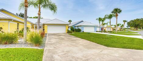A residential area with houses, a concrete driveway, and well-maintained lawns.