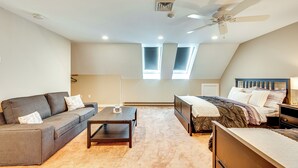 A bedroom with a bed, a sofa, a coffee table, and a ceiling fan. - Lake & Beach Access: Family Townhome in Laconia (Laconia)