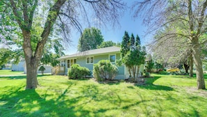 A single-story house with a front porch, surrounded by a well-maintained lawn and trees. - 10 Mi to Downtown: Group Getaway in Minneapolis (Brooklyn Center)