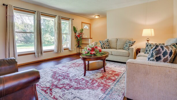 A living room with a sofa, armchair, and a coffee table with a floral arrangement. - 10 Mi to Downtown: Group Getaway in Minneapolis (Brooklyn Center)