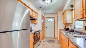 A kitchen with wooden cabinets, a stainless steel refrigerator, a built-in oven, and a granite countertop. - 10 Mi to Downtown: Group Getaway in Minneapolis (Brooklyn Center)