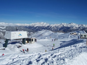 Une station de ski enneigée avec un chalet, des remontées mécaniques et des skieurs.