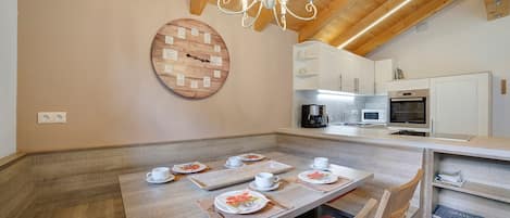 A dining area with a wooden table set for four, a chandelier, and a clock on the wall.