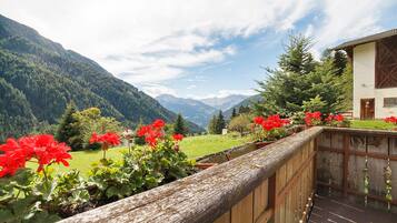 Une clôture en bois offrant une vue sur un paysage montagneux et un bâtiment doté d’un toit en pente.