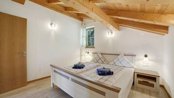 Ein Schlafzimmer mit Holzbalkendecke, einem Bett mit Kopfteil, Nachttischen und einem Fenster mit Aussicht.