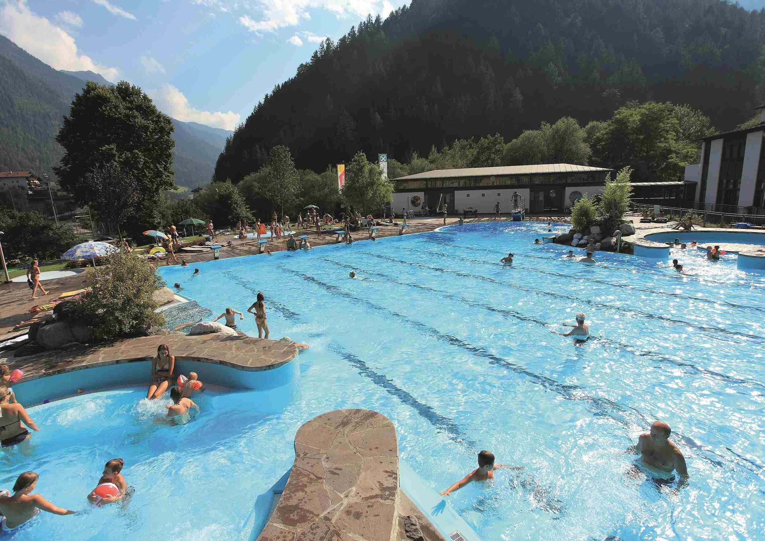 A pool area with multiple swimming pools, surrounded by trees and buildings.