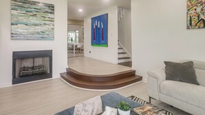A modern living room with a fireplace, a staircase, and a dining area in the background. - Spacious Home w/ Game Room, 2 Mi to Concord Mills! (Concord)
