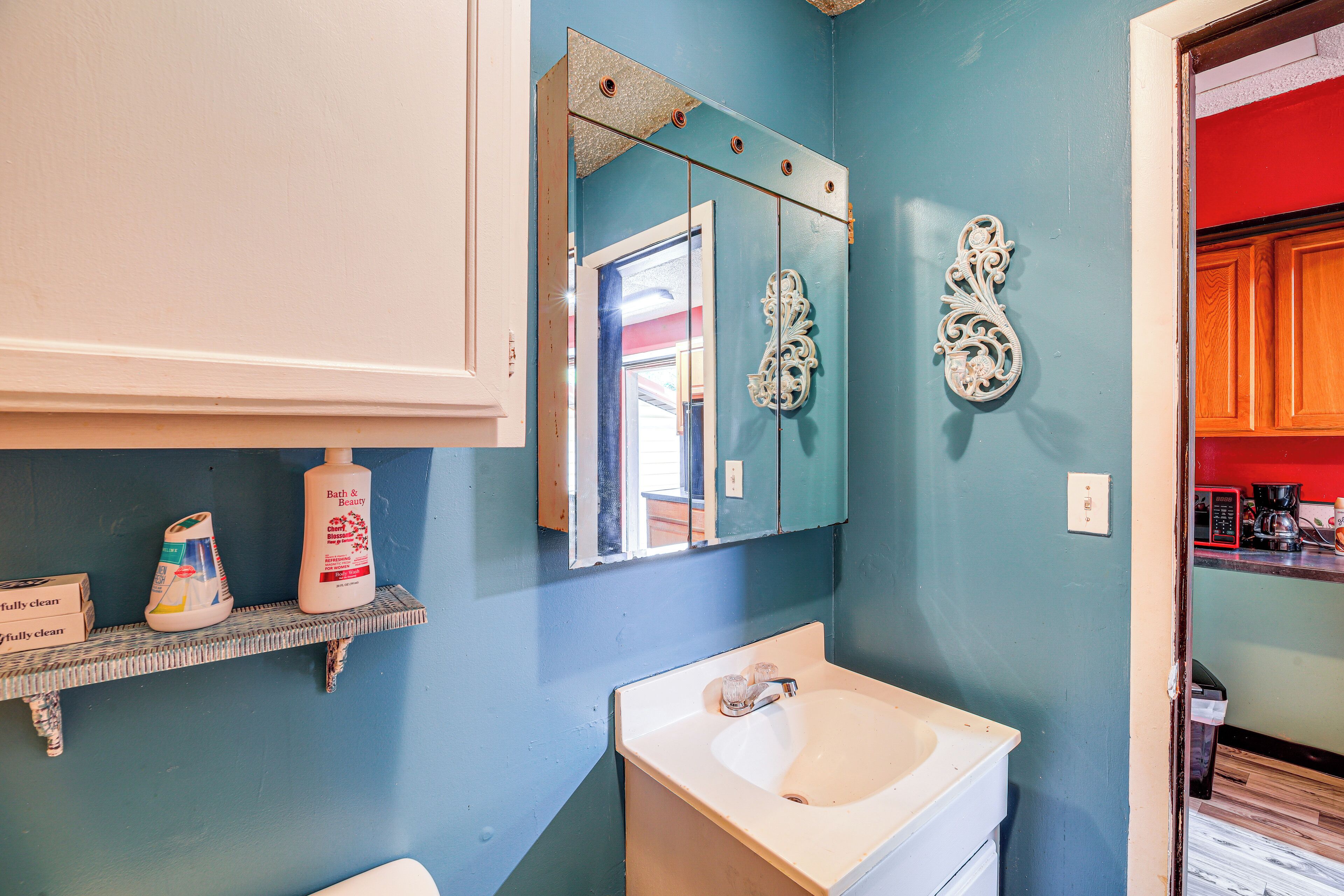 A bathroom with a sink, mirror, and decorative wall piece.