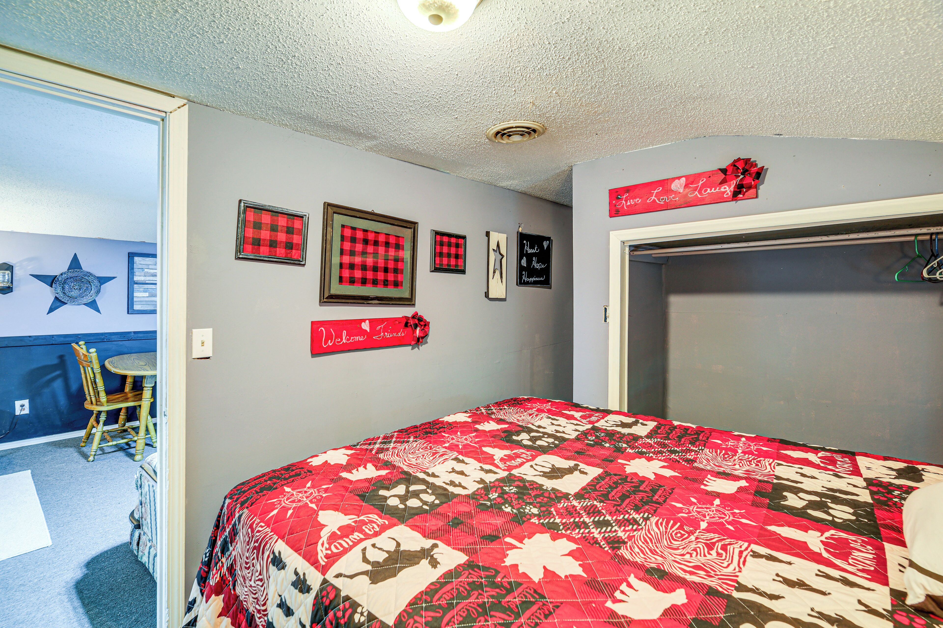 Une chambre avec un couvre-lit matelassé rouge et blanc, une chaise en bois, une petite table et une armoire avec un miroir.