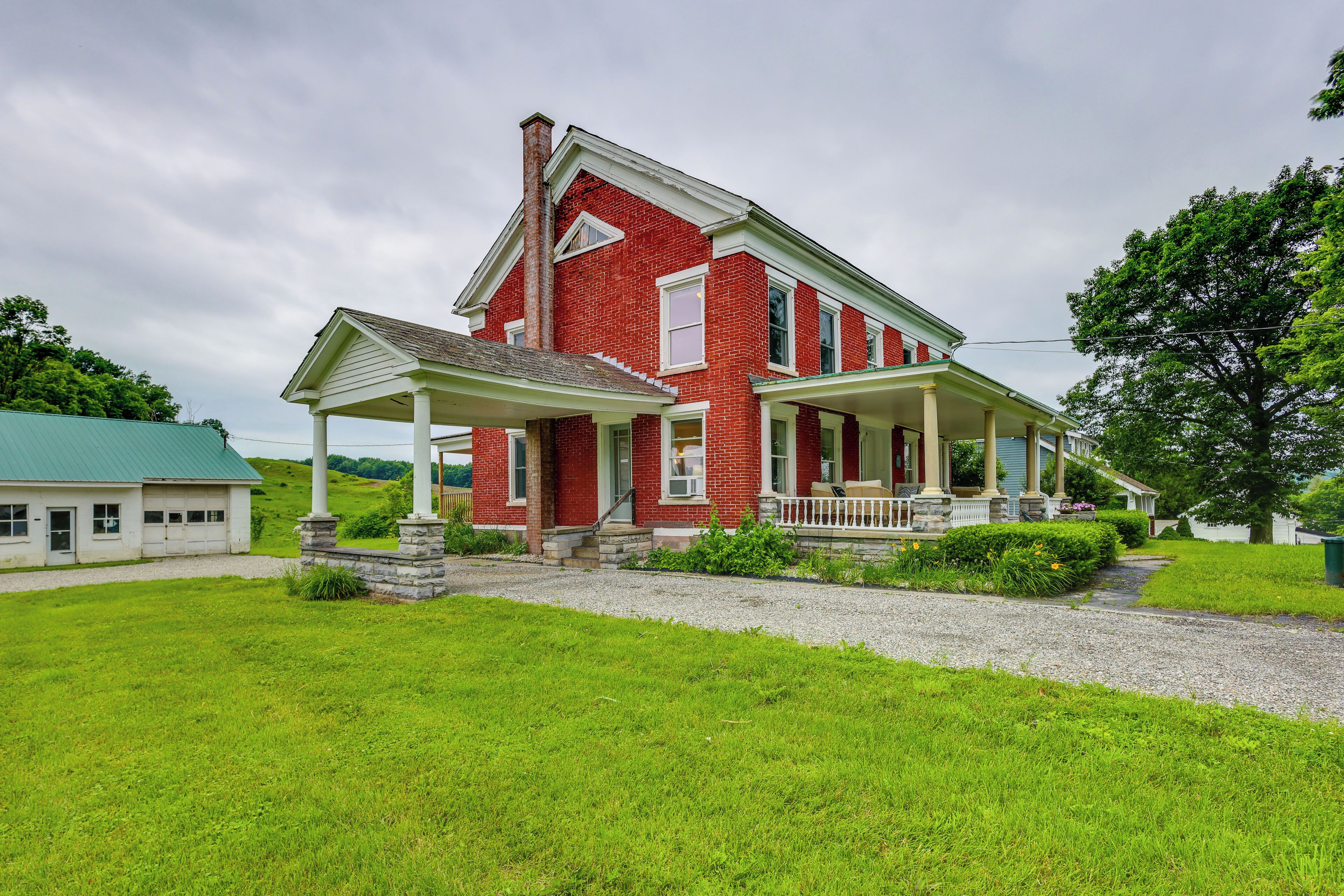 A two-story red brick house with a covered porch and a stone foundation.