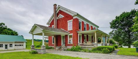 A two-story red brick house with a covered porch and a stone foundation.