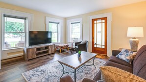 A living room with a flat-screen TV, a coffee table, a sofa, and a lamp. - Renovated 1800s Brick Farmhouse in Granville (Granville)