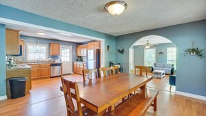 A spacious dining area with a wooden table and chairs, a kitchen with wooden cabinets and a dishwasher, and a living area with a sofa and a ceiling fan. - Hike, Fish & Ride: Pet-friendly Huntsville Home (Huntsville)