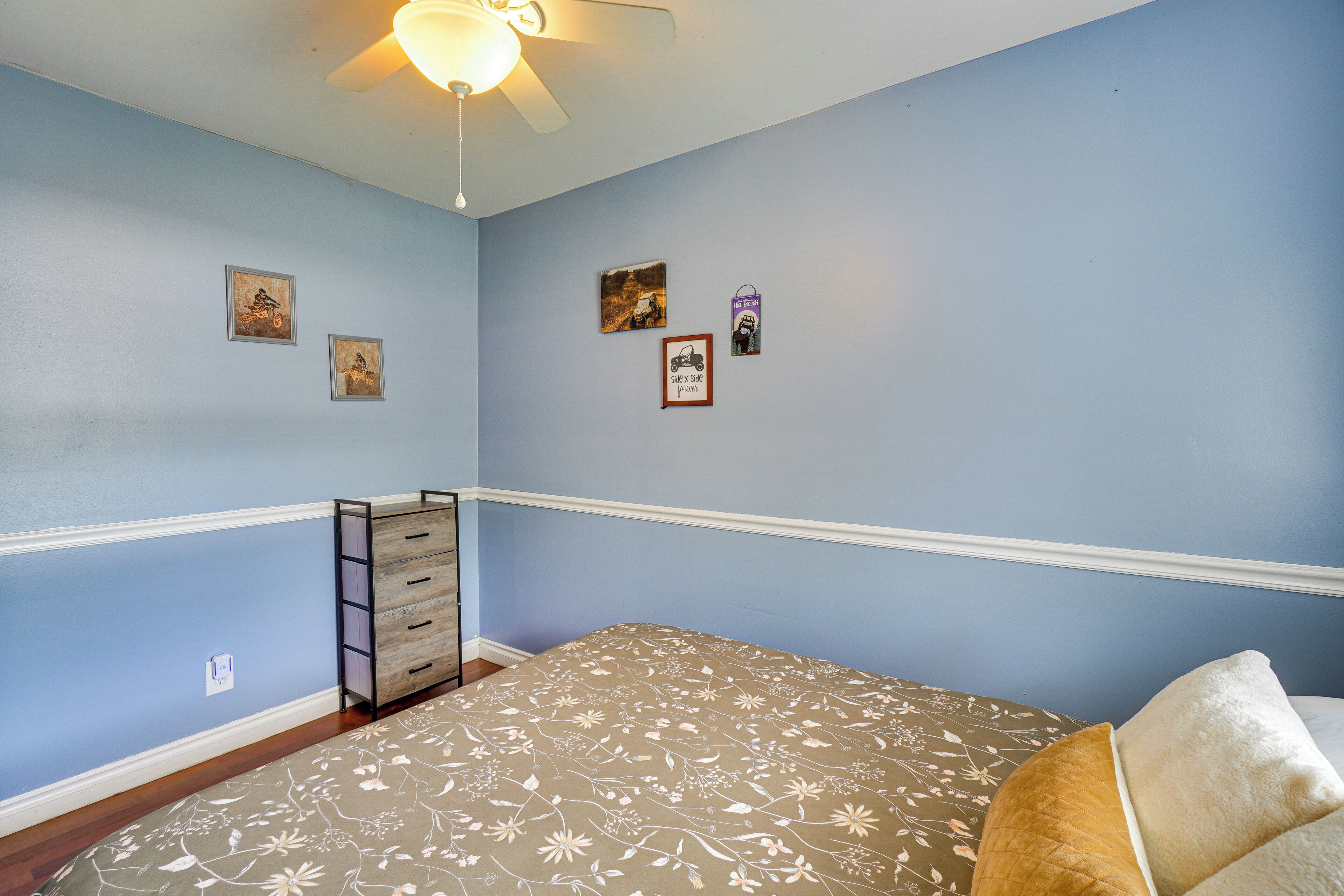 A bedroom with a bed, a dresser, and a ceiling fan.