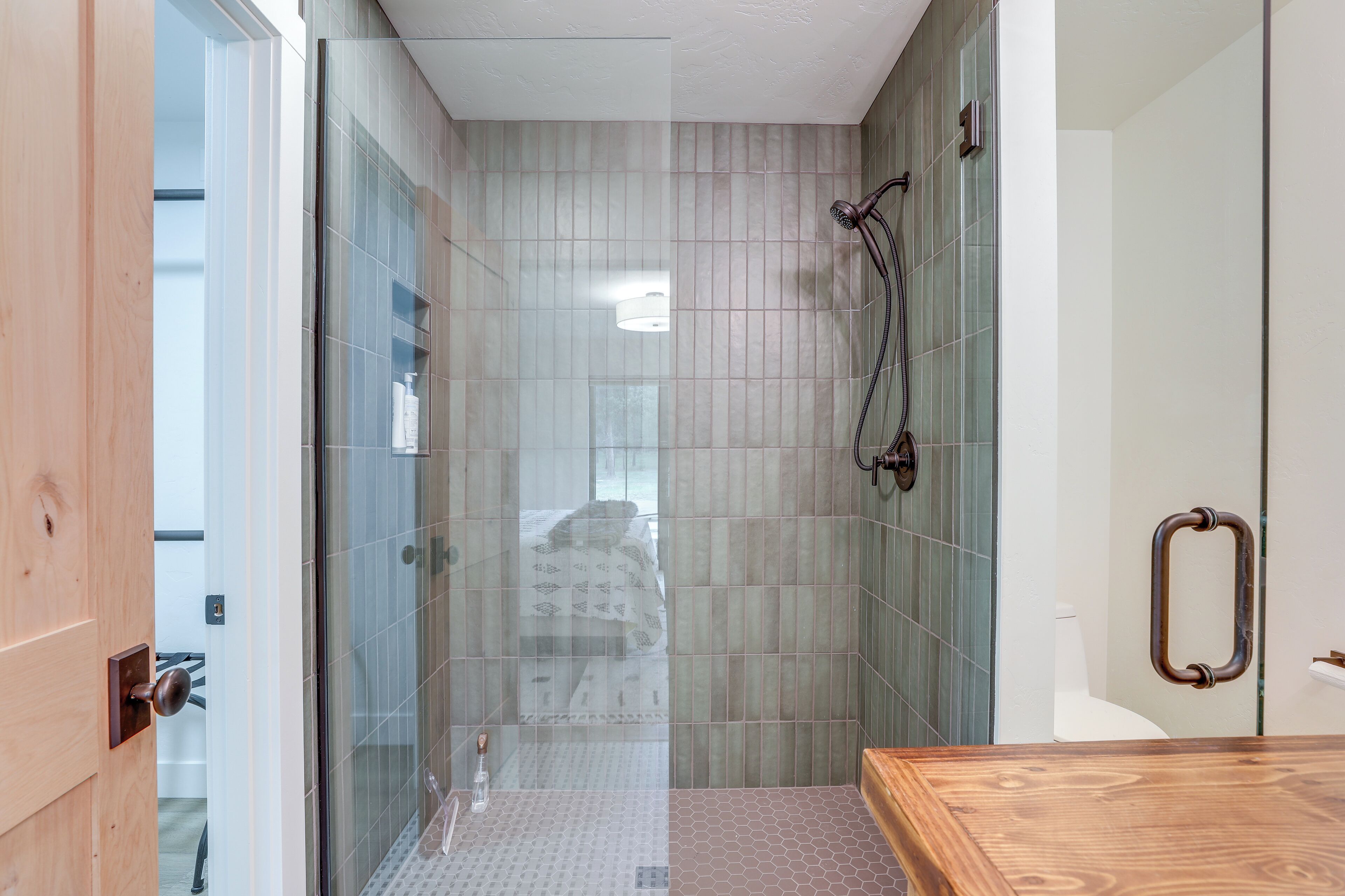 A modern bathroom with a glass shower enclosure, a wooden vanity, and a toilet with a towel rack.