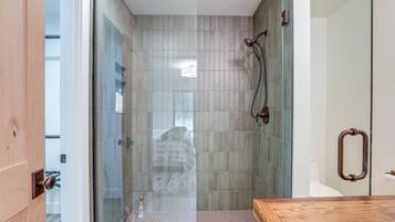 A modern bathroom with a glass shower enclosure, a wooden vanity, and a toilet with a towel rack.