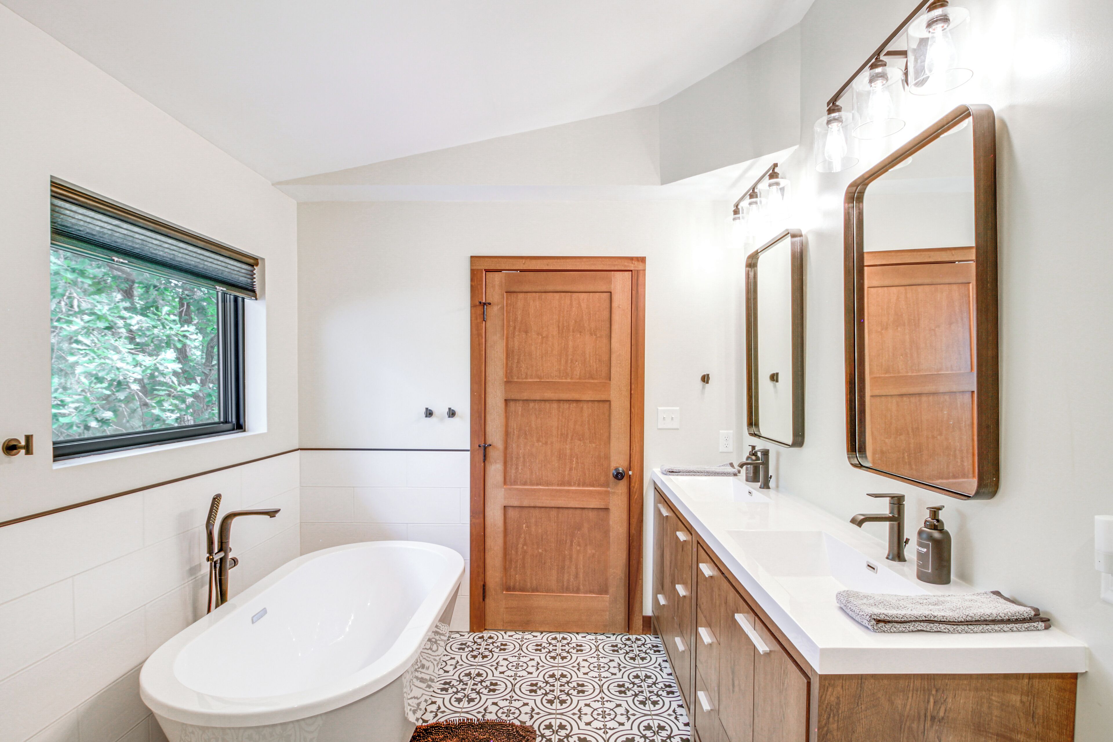 A modern bathroom with a freestanding bathtub, a double sink vanity, and a large mirror above the vanity.