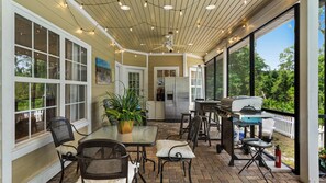 Un patio al aire libre con una parrilla, asientos y un refrigerador.