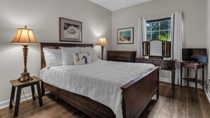 Un dormitorio con una cama grande, dos lámparas de noche, un aparador, un espejo y un televisor.