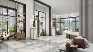 A spacious living area with a modern sofa, a coffee table, and a bookshelf. There are large windows providing a view of the city. - Delujo Stays – Burj Crown Collection (Dubai)